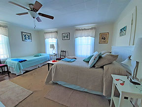 Guest room with queen bed on right and twin bed on left with seating area in between
