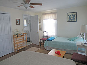 Guest room with twin bed on right opposite entrance to in-suite bath.  Queen bed is in foreground